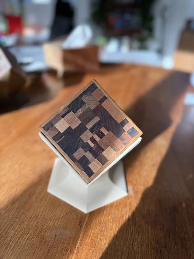 A coaster set with a dark end-grain mosaic on a white stand