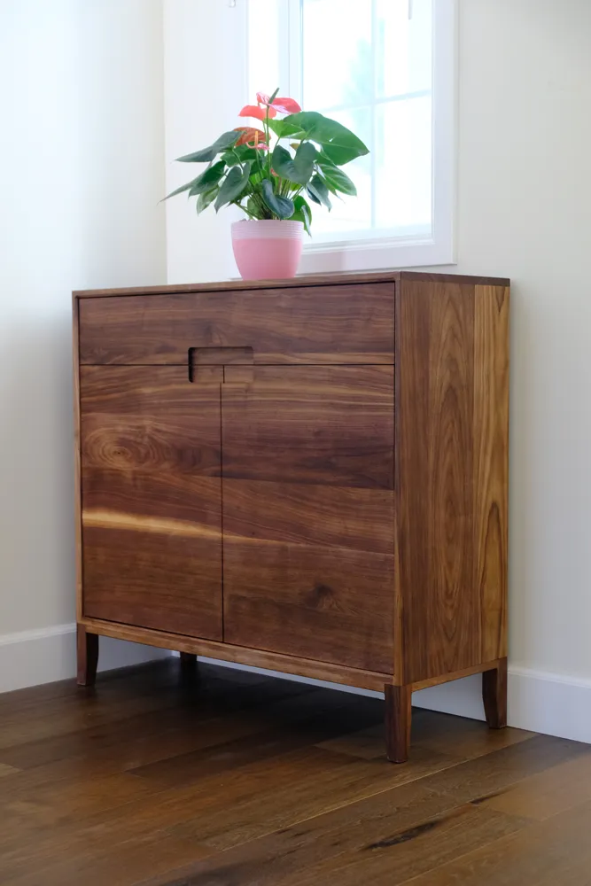 Black walnut entryway cabinet with grain running continuous across the front
