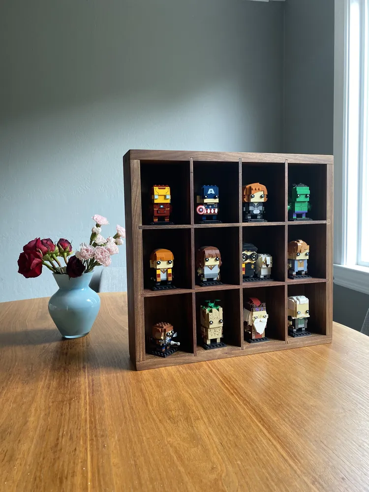 Black walnut grid shadow box displaying LEGO BrickHeadz figures, beside flowers