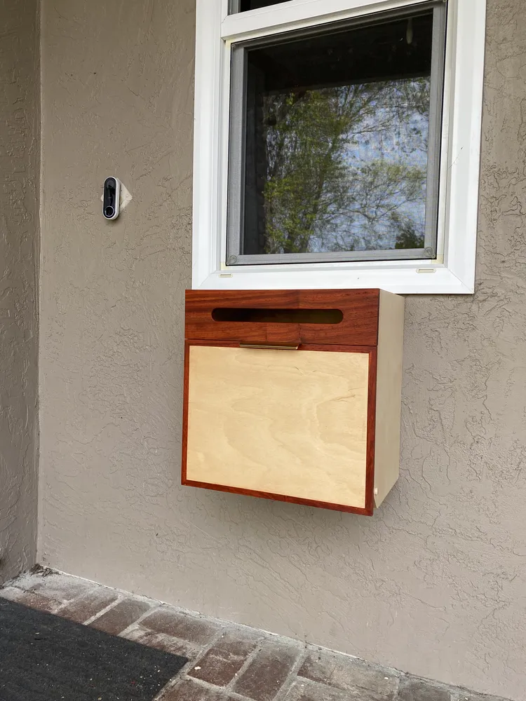 Wall-mounted mailbox with a padauk frame over a maple-plywood drop-down door