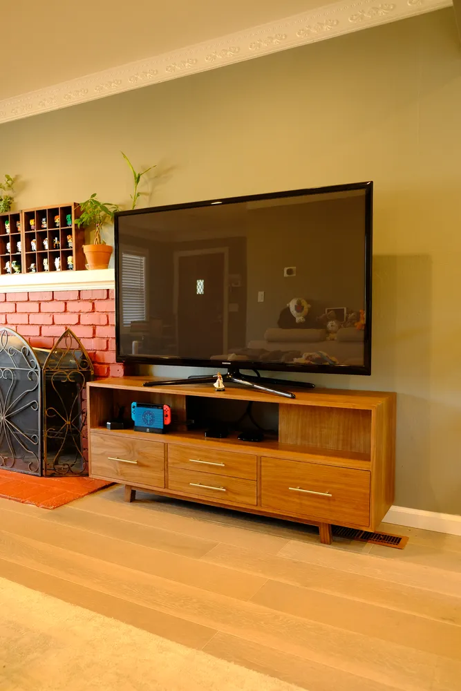 Low black walnut TV credenza with four drawers and an open center cubby on angled legs