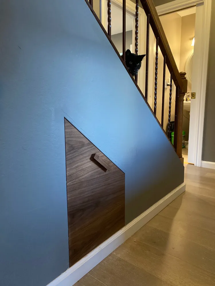 Pull-out shoe-rack drawer faced in black walnut, fitted into the space under the stairs
