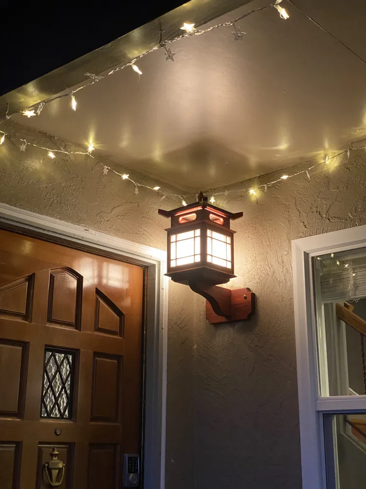 The lantern installed and lit beside a front door at night