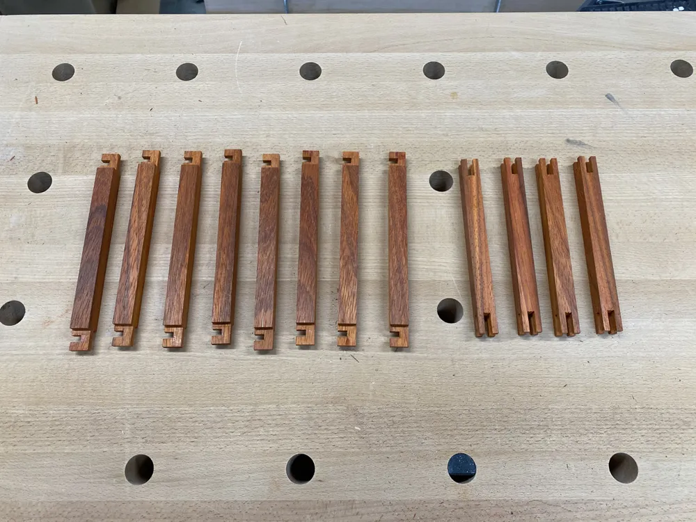 Milled padauk slats with cut notches on a workbench